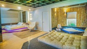 A modern bedroom with a bed, a seating area, and a bathroom. - Motel Chavelle (Sao Jose dos Pinhais)