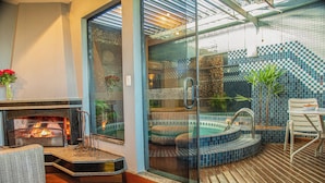 A modern interior with a fireplace, a glass-enclosed hot tub, and a wooden deck. - Motel Chavelle (Sao Jose dos Pinhais)