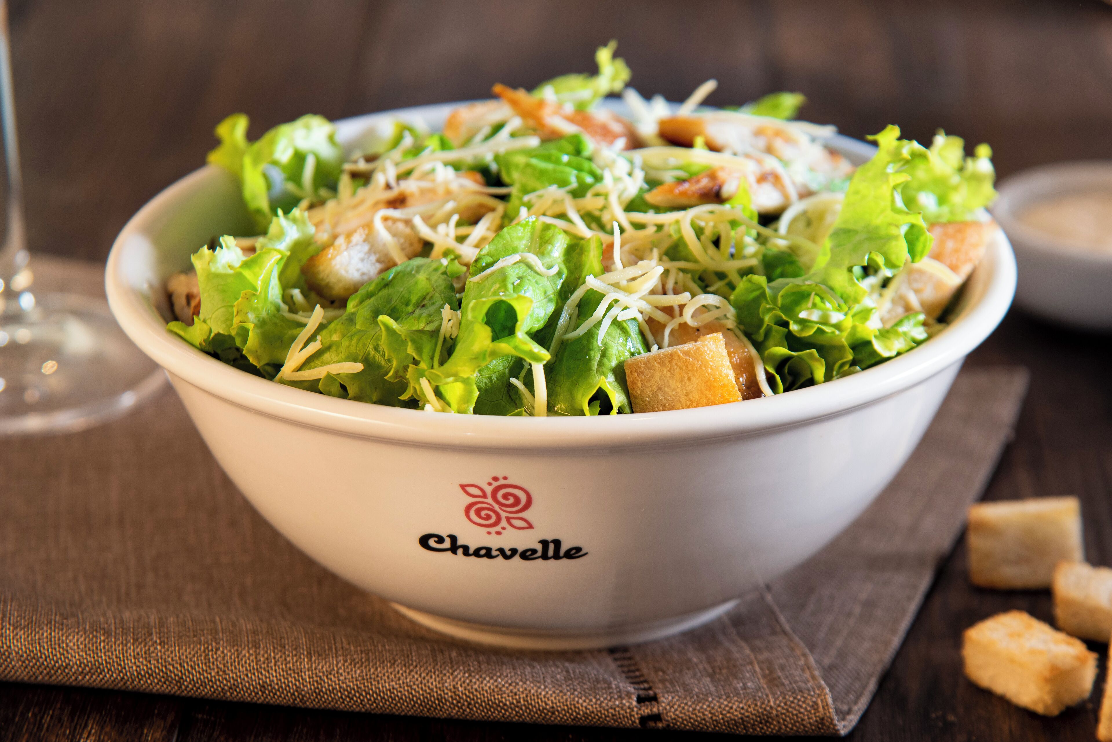 Un tazón de ensalada con crutones y queso rallado, etiquetado como 'Chavelle'.