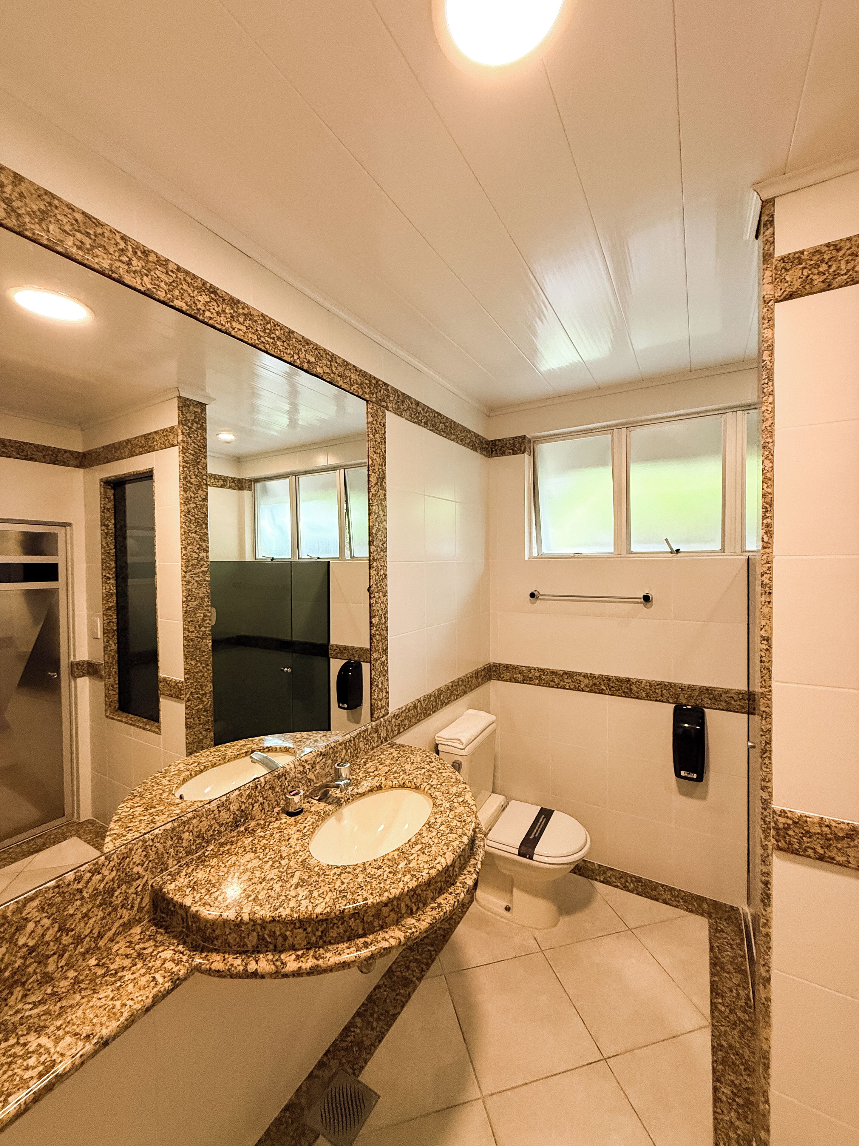 A bathroom with a granite countertop sink, a toilet, and a shower area.