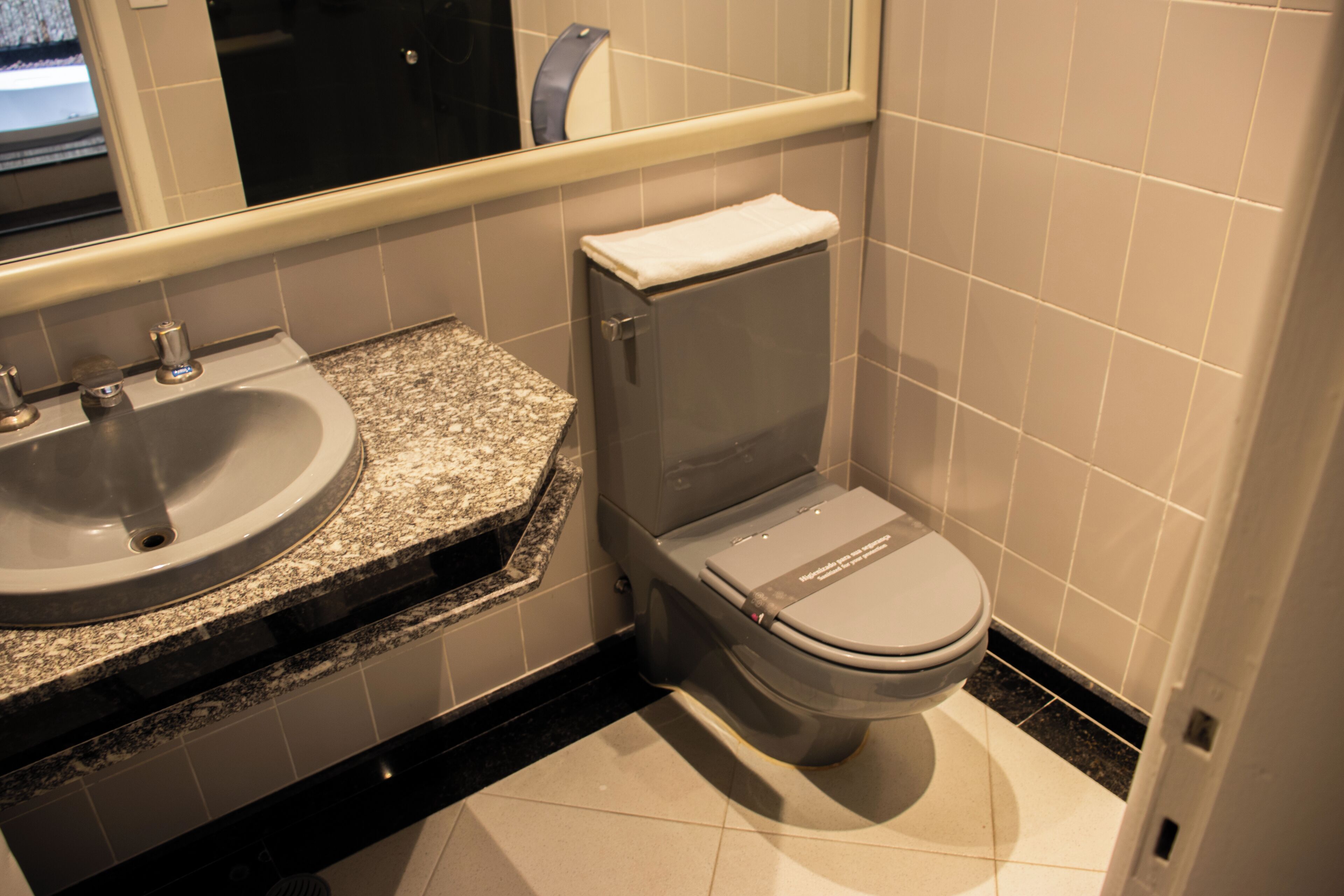 A bathroom with a granite countertop sink, a toilet, and a mirror above the sink.