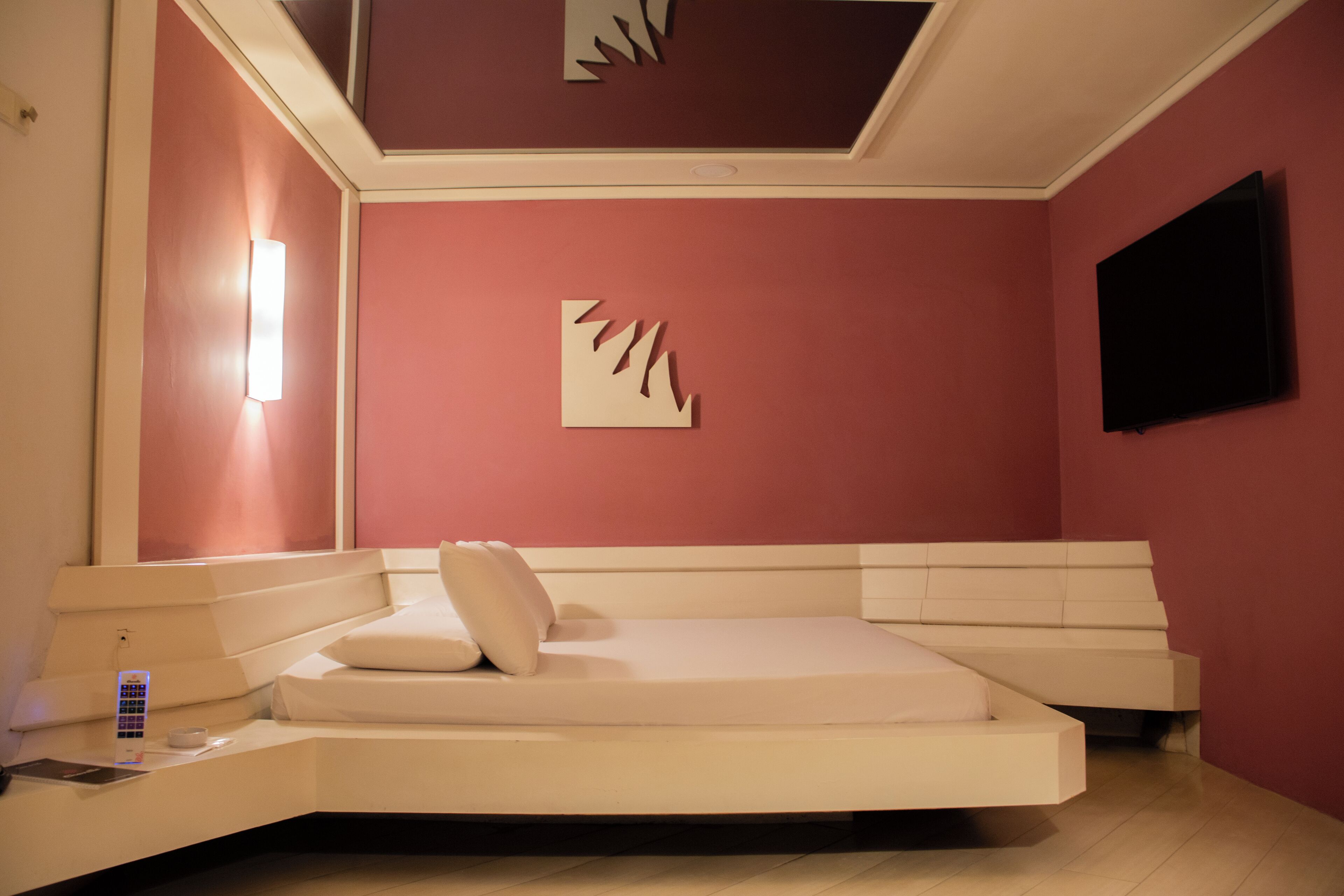 Un dormitorio moderno con un diseño de cama curvada, un televisor de pantalla plana en la pared y una estética minimalista.
