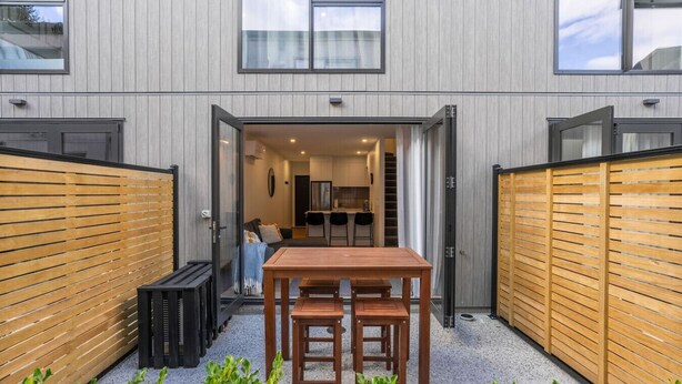 A modern building with a wooden fence, a table, and chairs in the courtyard. - Ride Recover & Rest | Arthurs Point Stay Near Ski & Hot Pools (Queenstown)