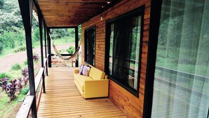 Une terrasse en bois avec un canapé jaune et un hamac.