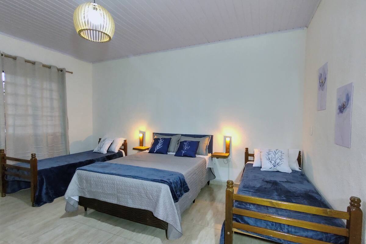 A room with three single beds, each with a wooden headboard and a bedside table.