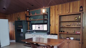 Une cuisine avec des meubles de rangement en bois, une table à manger en bois avec des tabourets, et une fenêtre donnant sur un beau paysage.