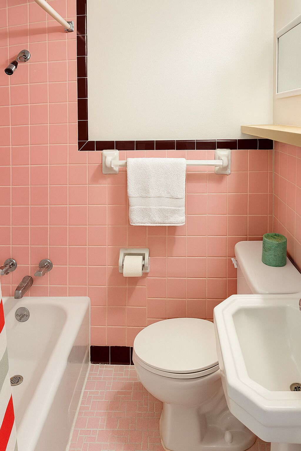 A bathroom with pink tiles, a white toilet, a white sink, and a bathtub.