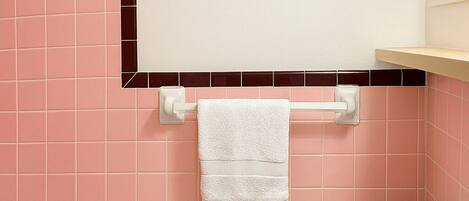 A bathroom with pink tiles, a white toilet, a white sink, and a bathtub.