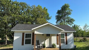 Ein kleines, eingeschossiges Haus mit einer Veranda, einer Holzterrasse und einer Garage.
