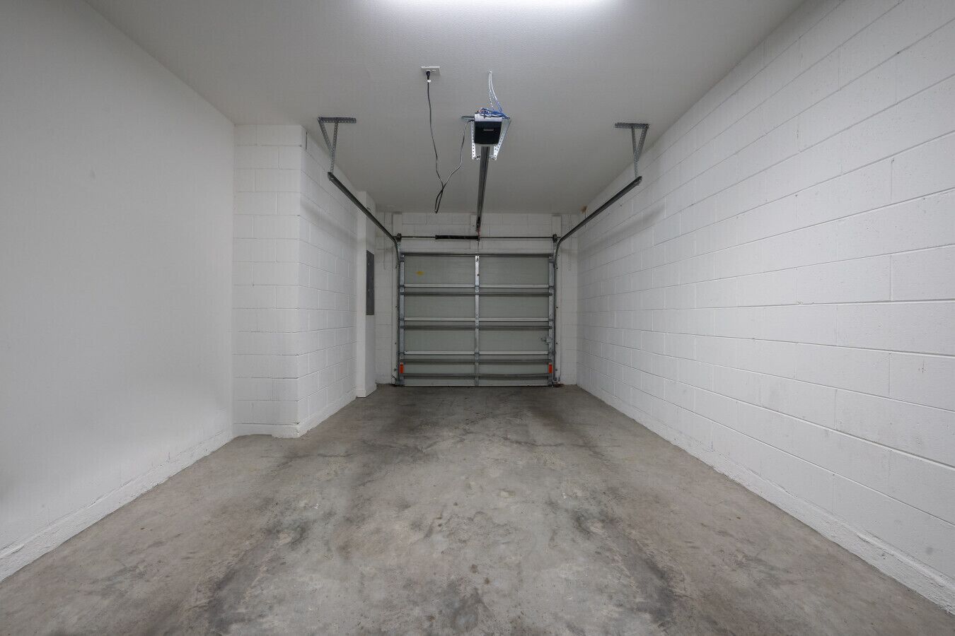 A clean, empty garage with white brick walls and a concrete floor.