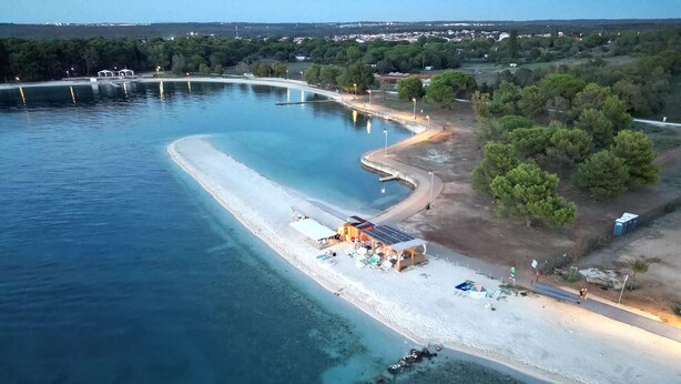 An aerial view of a coastal area with a sandy beach, a small pier, and a few buildings. - Awesome home in Fazana (Fazana)