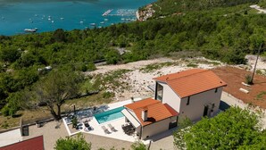 A modern villa with a swimming pool, surrounded by lush greenery and overlooking a coastal bay with boats. - Luxurious home in Trget (Trget)