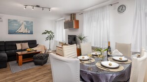 A modern living room with a sofa, a dining table set for four, and a television. - Lovely home in Selce with WiFi (Selce)