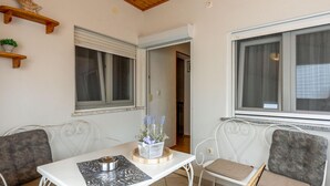 A small, cozy room with a white table, two chairs, a window with curtains, and a wooden shelf with a star decoration. - Lovely home in Selce with WiFi (Selce)
