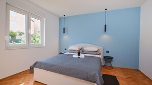Ein Schlafzimmer mit einem Bett, einem Fenster und einem kleinen Tisch mit Flasche und Gläsern.