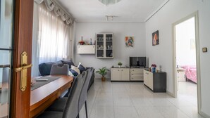 Un soggiorno moderno con divano, TV, armadietti e zona pranzo con tavolo e sedie.