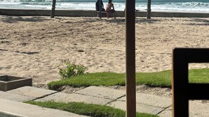 A beach volleyball court with a net, palm trees, and a view of the ocean.