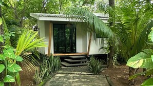 A small, modern building with a concrete pathway leading to a wooden deck.