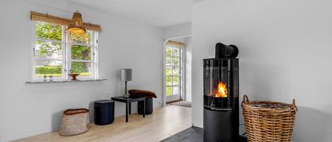 Un interior moderno con chimenea, suelo de madera y ventanas amplias.
