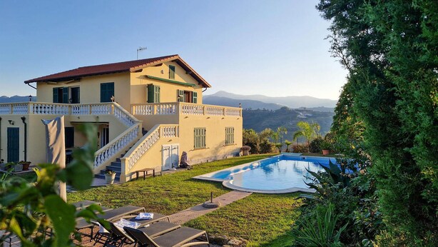 Une maison à deux étages avec une piscine, un escalier et une vue sur les montagnes en arrière-plan.