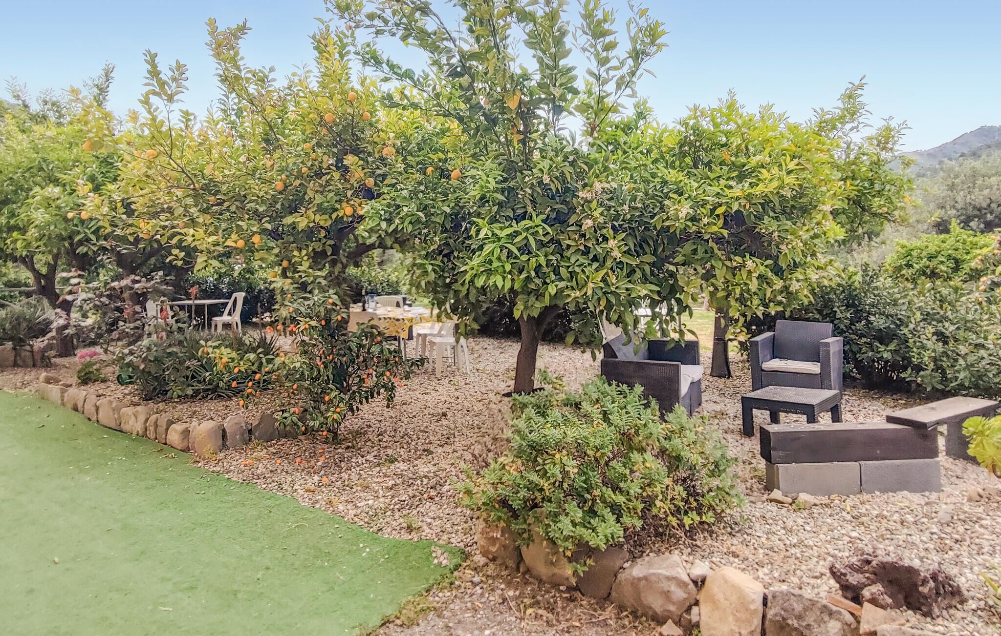 Un jardín ajardinado con árboles, zonas de estar y un césped verde.