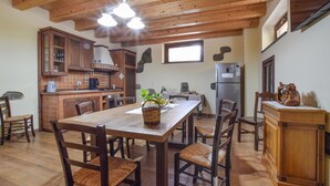 Une cuisine spacieuse avec des meubles de rangement en bois, une table à manger avec des chaises et un réfrigérateur.
