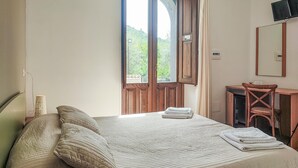 Une chambre à coucher comprenant un lit, un bureau, une chaise et une fenêtre donnant sur un paysage verdoyant.