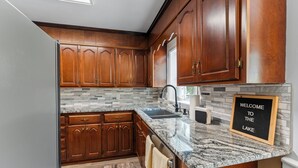 Una cocina con armarios de madera, encimera de granito y un cartel de bienvenida.