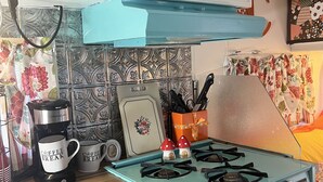 Et køkken med en turkis komfur, kaffemaskine og mikrobølgeovn.