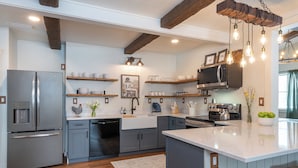Una cocina moderna con electrodomésticos de acero inoxidable, vigas de madera e iluminación colgante.