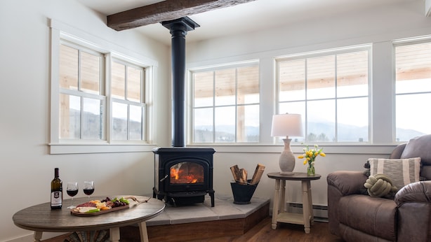 Una sala de estar acogedora con chimenea, una mesa de comedor con botella de vino y copas, y un sofá cómodo.