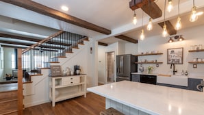 Una cocina moderna con una isla grande, piso de madera y vigas a la vista.