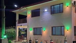 Un bâtiment à deux étages, doté d’une entrée couverte et de nombreuses fenêtres, chacune étant illuminée par des lumières vertes.