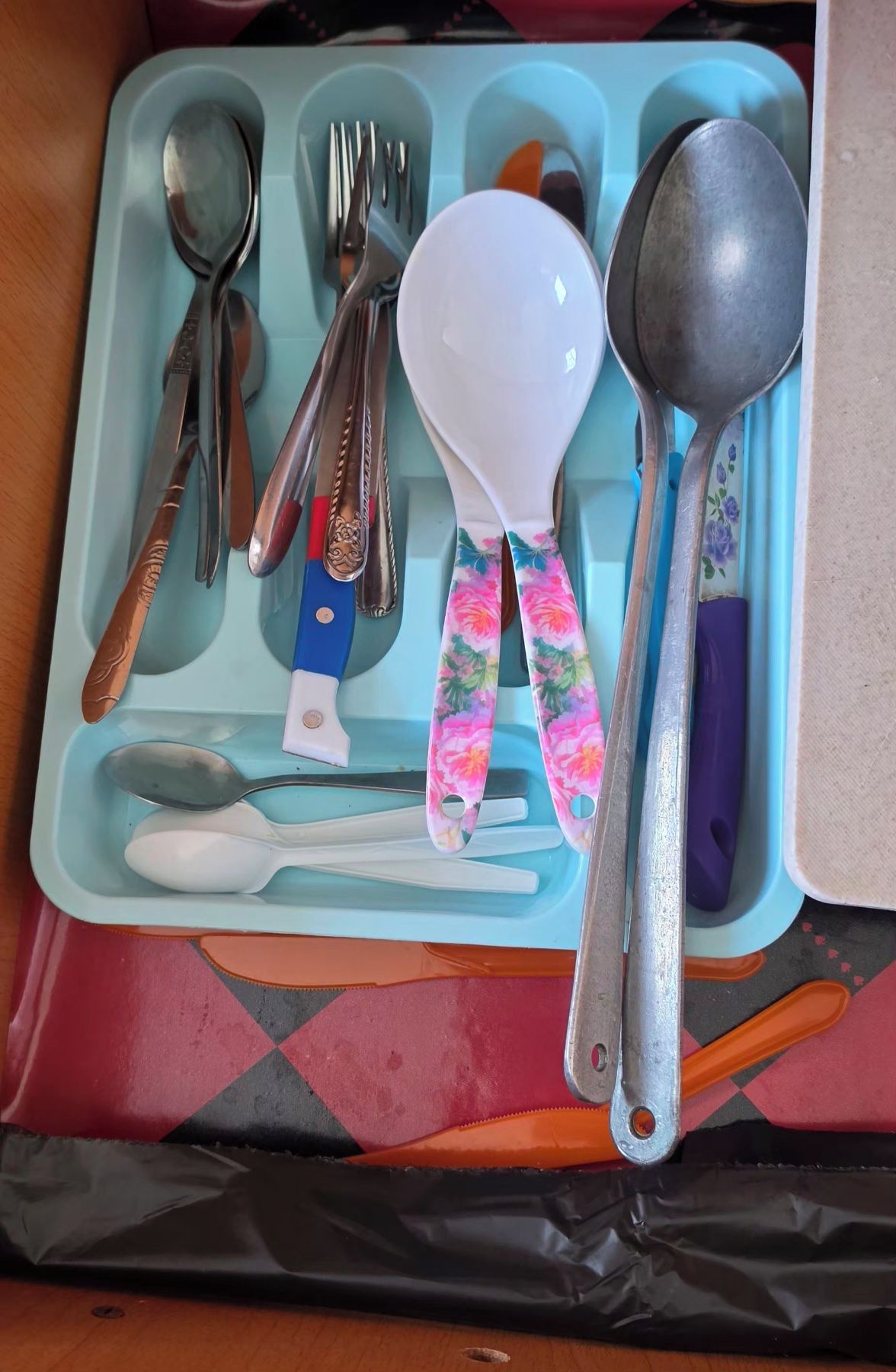 A set of cutlery including spoons, forks, and a knife, neatly arranged in a compartment.