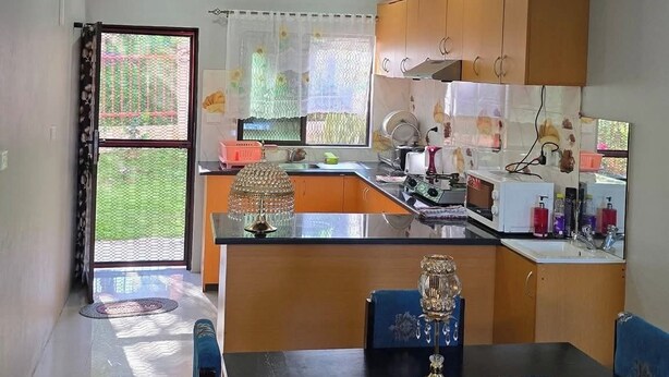 Une cuisine moderne avec des meubles en bois, un îlot central et un coin repas doté de chaises recouvertes de tissu bleu.