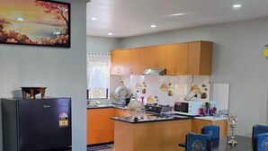 Une cuisine moderne dotée d’un îlot central, d’un réfrigérateur et d’un coin repas avec des chaises bleues.