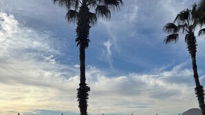Ein Poolbereich mit Liegestühlen und Sonnenschirmen, ein rotes Luftauto und ein Kreuzfahrtschiff im Hintergrund.