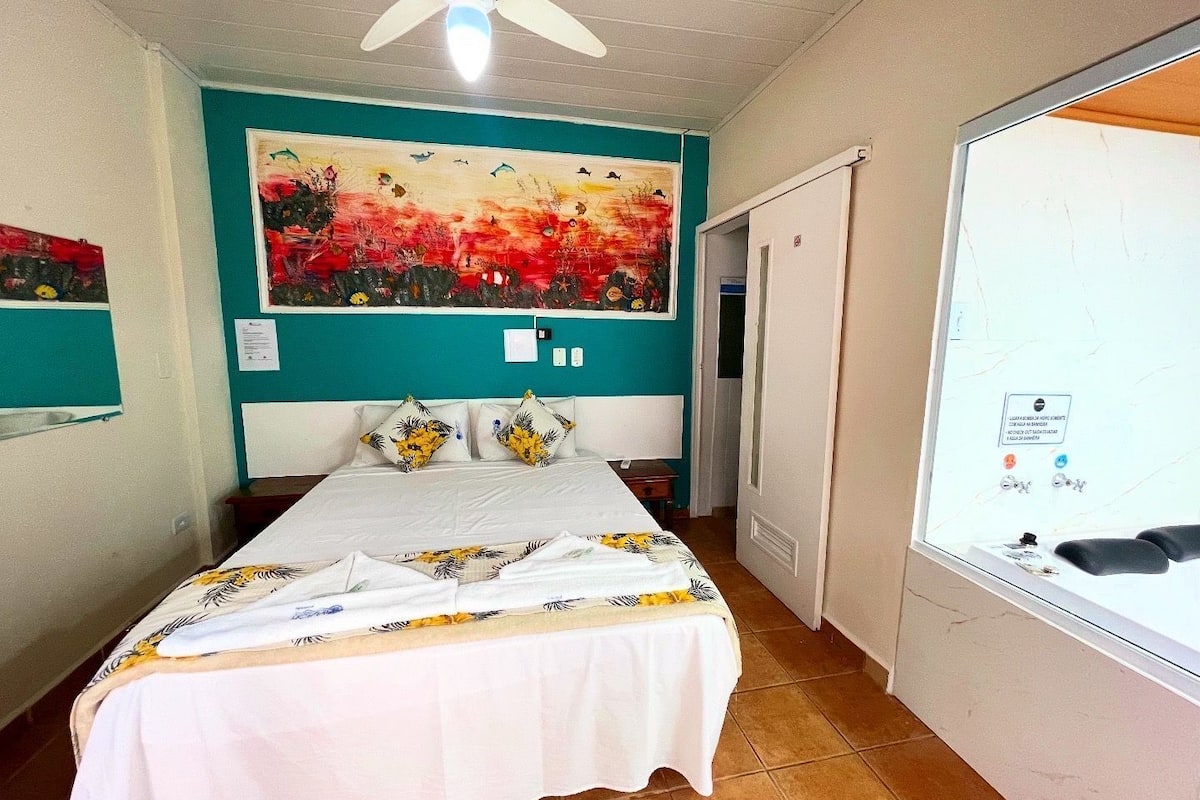 A bedroom with a bed, a ceiling fan, a large painting on the wall, and a window with stickers.