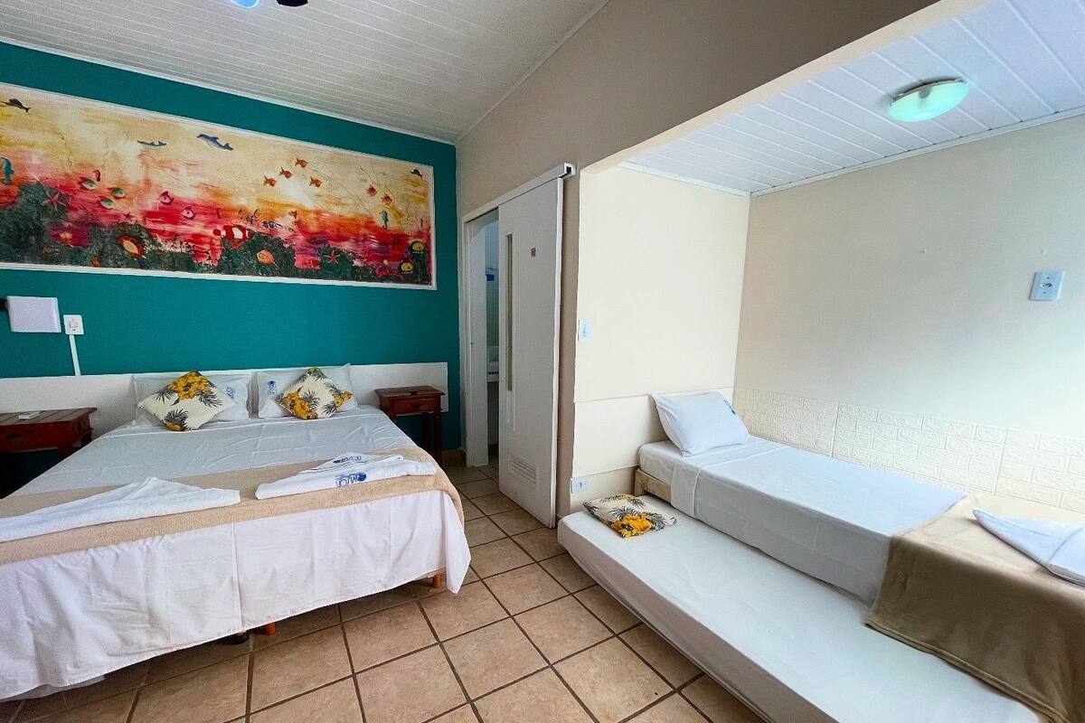 A hotel room with a bed, a sofa bed, a painting on the wall, and a tiled floor.