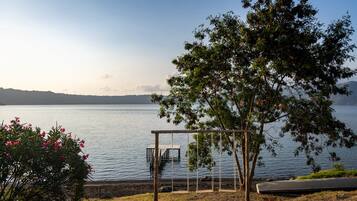 A lakeside view with a wooden swing set, a boat, and a clear sky.