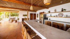 A modern kitchen with a long countertop, wooden cabinets, and hanging pendant lights.