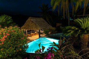 Private pool and palapa illuminated after sunset
