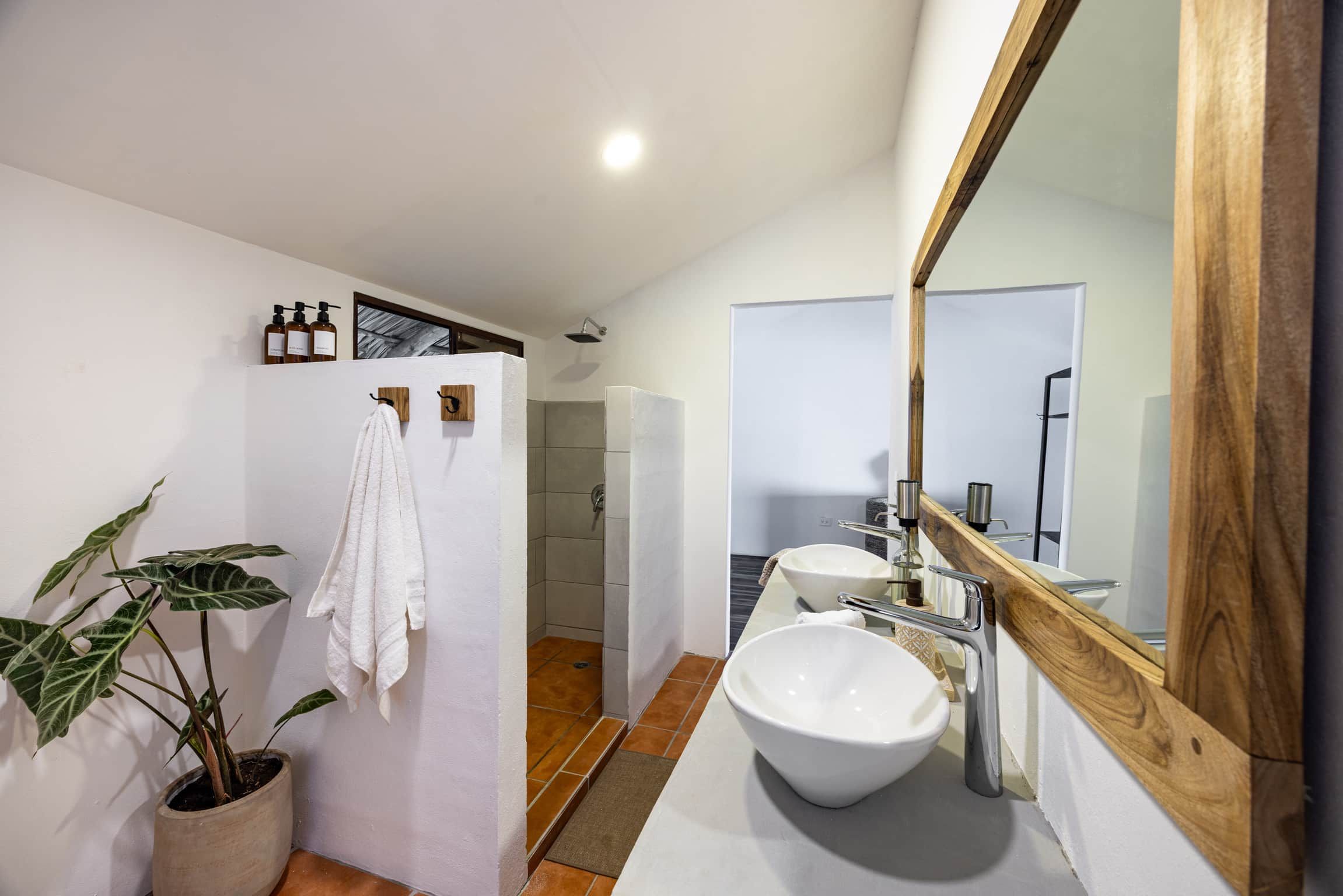 A modern bathroom with a large mirror, a white sink, and a shower area.