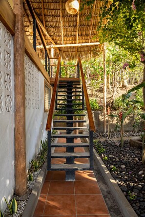 A staircase leading to a covered area with a thatched roof, surrounded by greenery and a garden. - Casa del Alma: Laguna Villa with Infinity Pool and Dock (La Laguna Número 1)