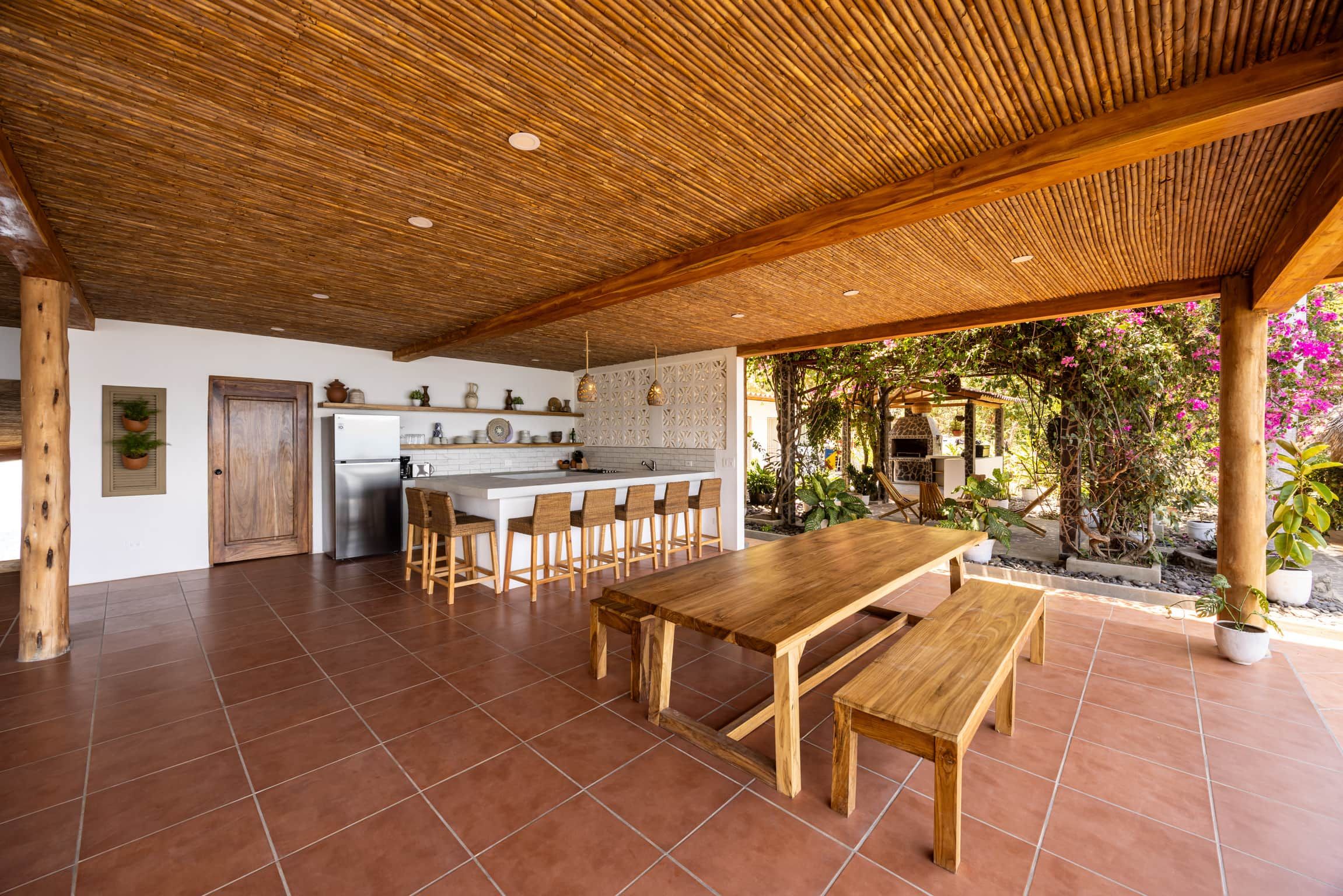 A spacious kitchen with a central island, wooden furniture, and a patio area with a pergola.