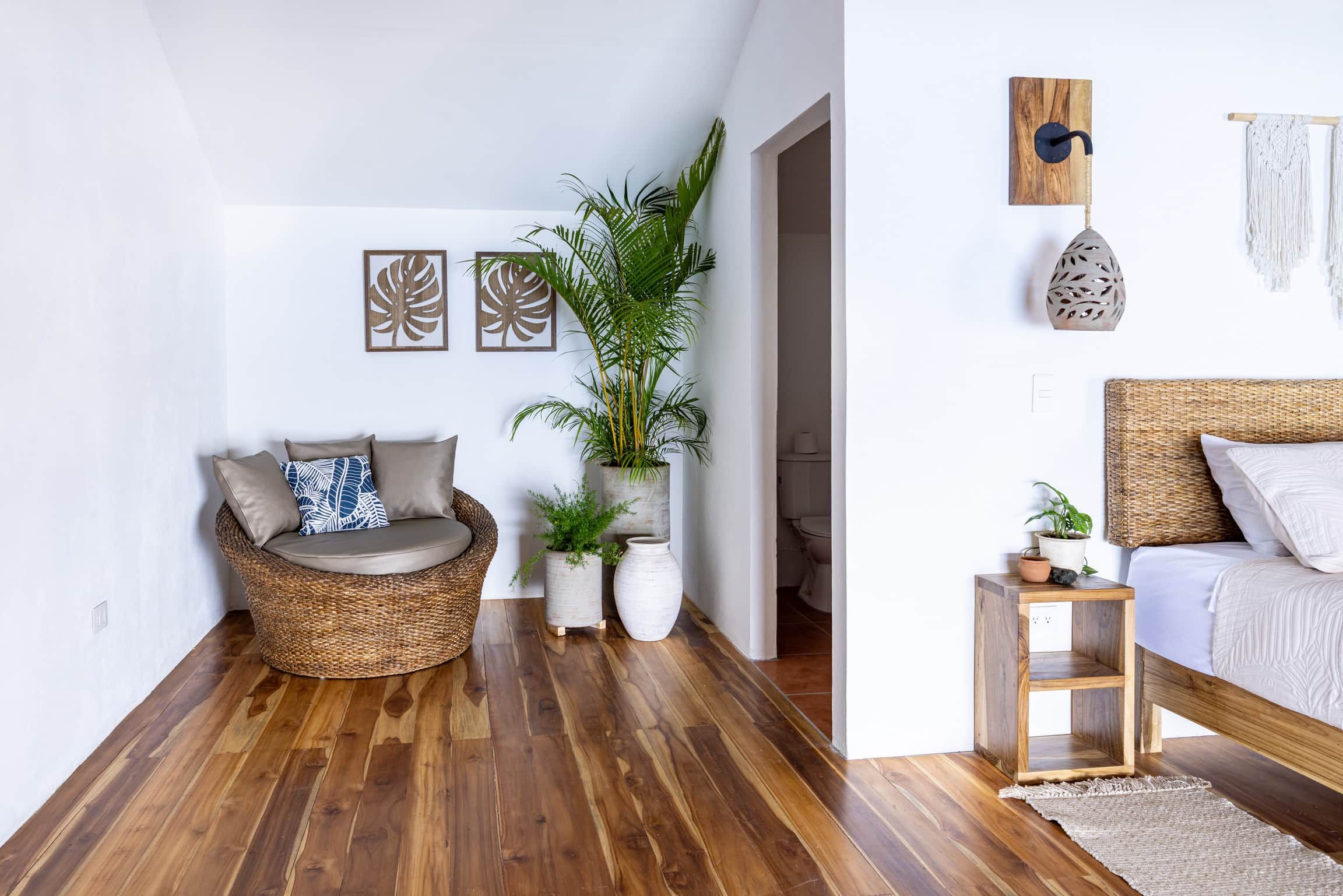Un espacio habitable moderno con un sofá de mimbre, una cama y una pequeña mesa de madera.