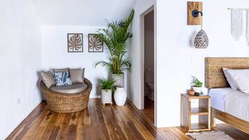 Un espacio habitable moderno con un sofá de mimbre, una cama y una pequeña mesa de madera.