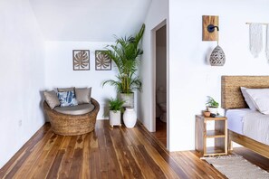 A modern living space with a wicker sofa, a bed, and a small wooden table. - Casa del Alma: Laguna Villa with Infinity Pool and Dock (La Laguna Número 1)
