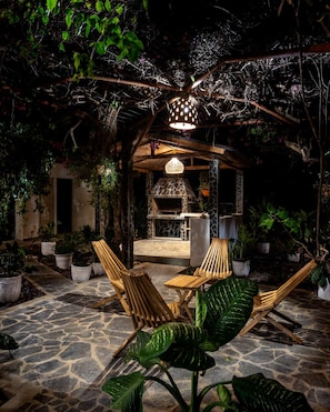 An outdoor patio with stone flooring, wooden furniture, and a stone-built barbecue area. - Casa del Alma: Laguna Villa with Infinity Pool and Dock (La Laguna Número 1)