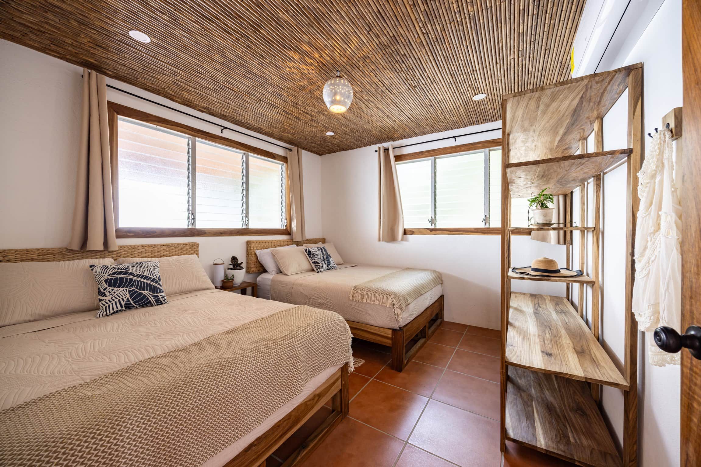 Una habitación con dos camas, techo de madera y ventana con vistas.